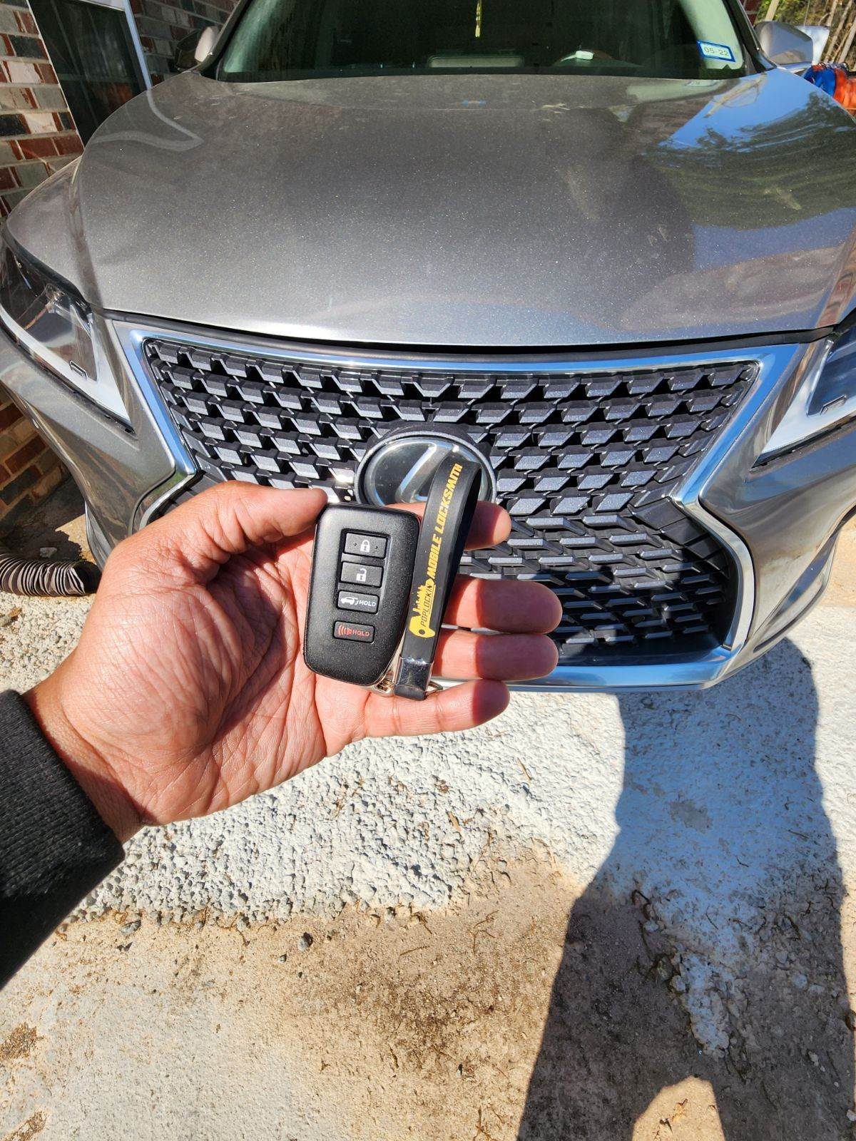 Poplockin mobile locksmith handing over freshly programmed Genesis smart keys next to client vehicle in Metro Atlanta